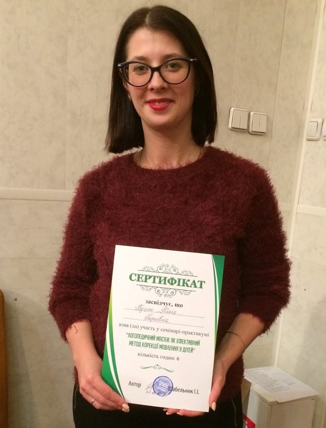 Yuliia Butsiak holding a certificate from a speech therapy training seminar